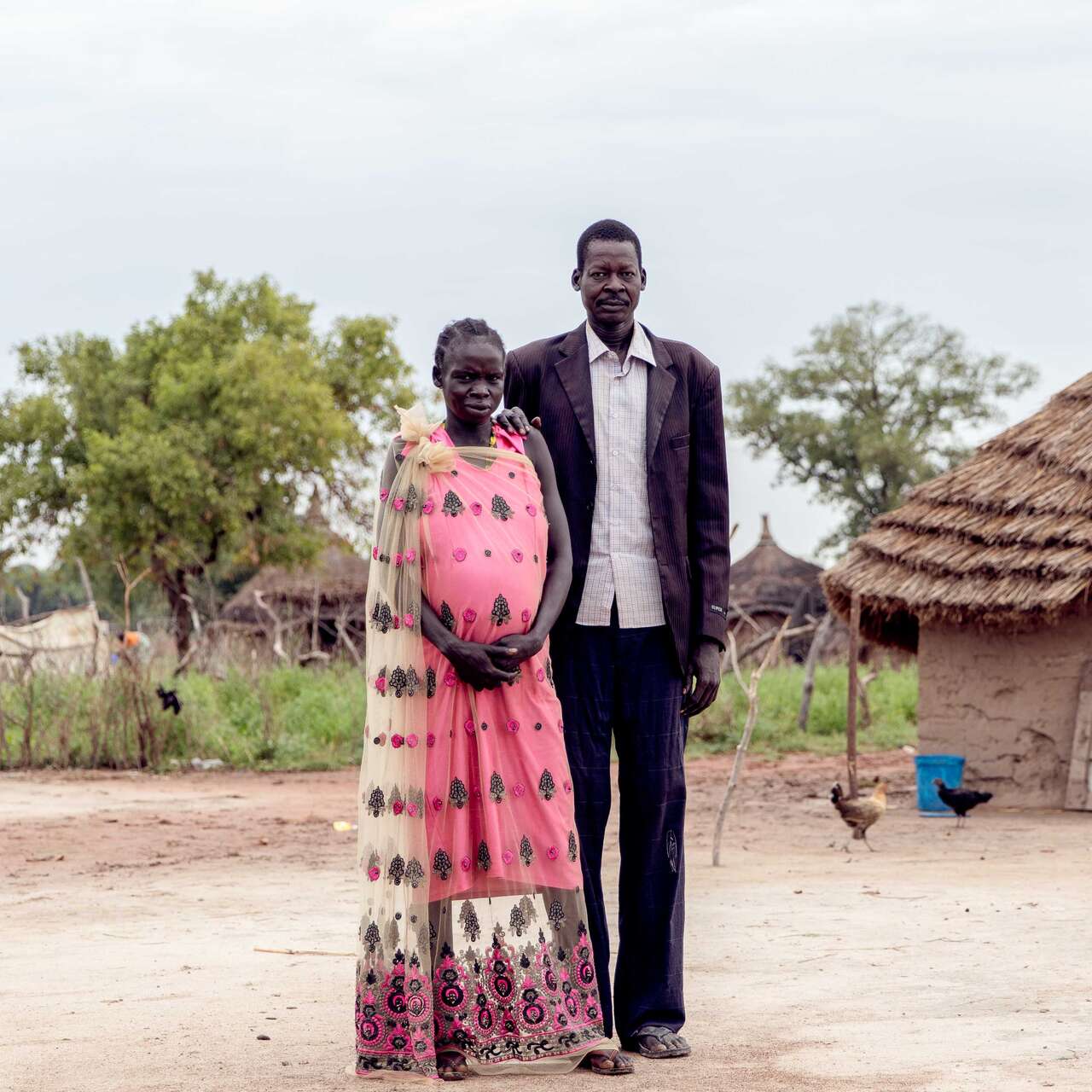 A man and woman embrace while posing for a photo outside their home in South Sudan.